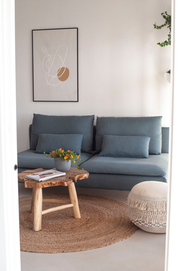 Un salón con sofá y sillón con una planta en la pared.