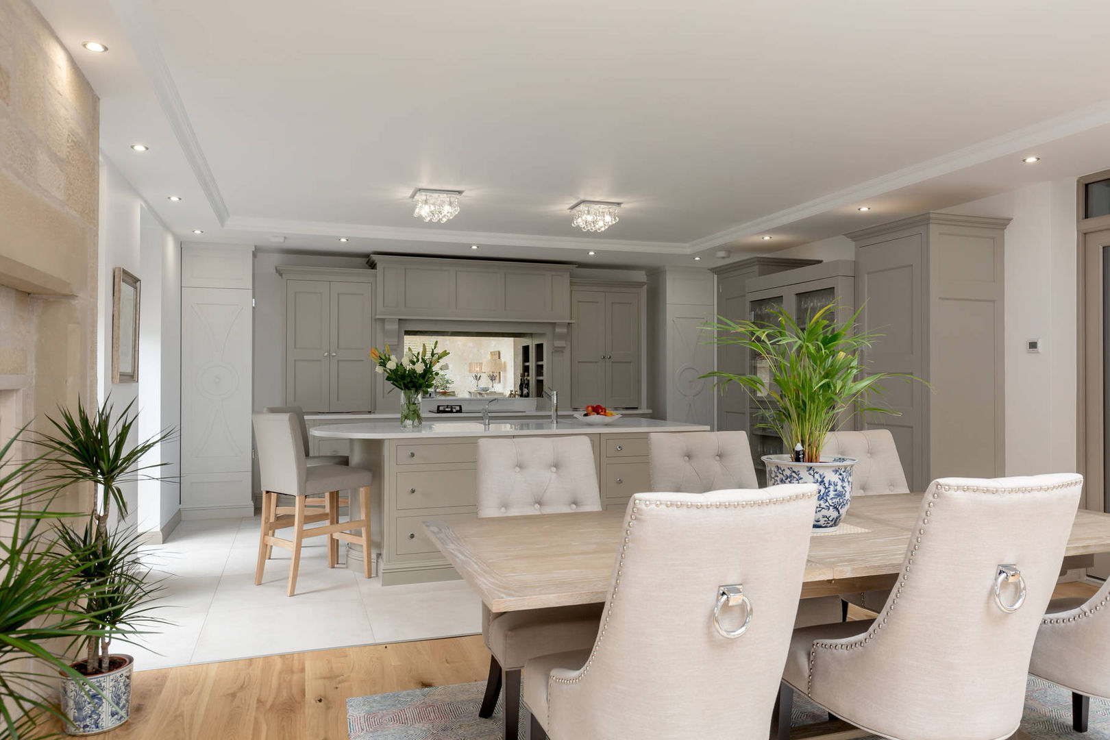 Kitchen diner in grey by Christopher Howard Christopher Howard Classic style dining room Wood Wood effect Grey kitchen, grey beige kitchen, griege colour scheme, kitchen diner, traditional kitchen, kitchen with island, tile floor, kitchen mantle, glass back splash, antique glass splashback, white floor, white worktop, open plan living, upholstered dining chairs