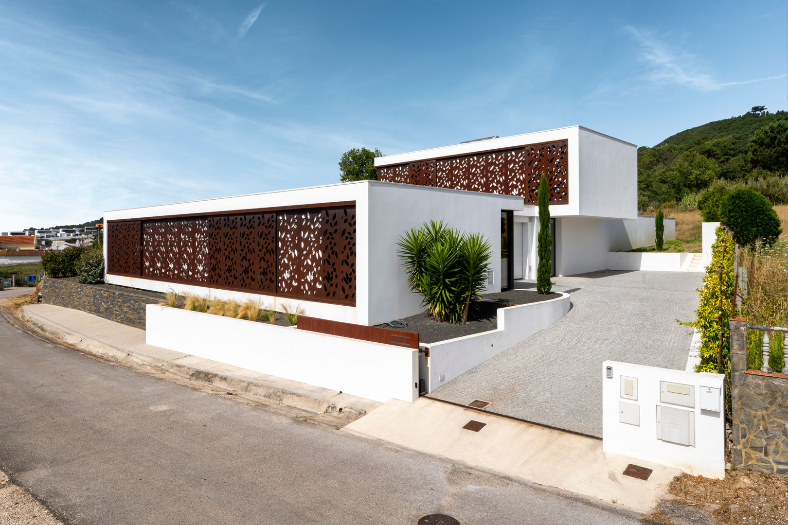 House "Lopes" - Front of the house Pascal Millasseau Construction Eengezinswoning steel corten front house modern white block entry garage floral elegant villa high-end
