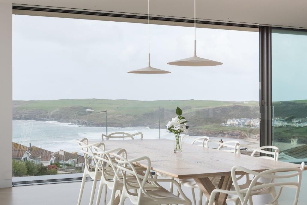 Dining room with full height windows Arco2 Architecture Ltd Ruang Makan Modern Architecture Cornwall, Architecture Polzeath, Polzeath, Cornwall, Eco-friendly, eco friendly, sustainable, environmentally friendly, green roof, newspaper insulation, surf room, reverse living, inside outside living.